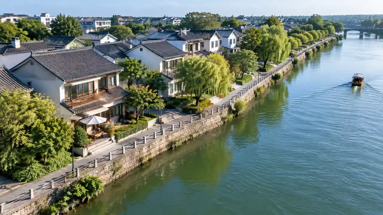 沿河街区低空斜拍：河堤、栏杆与临街建筑依次排开