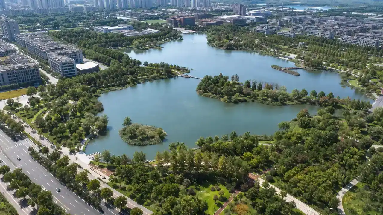 城市上游水库与曲折岸线的航拍画面,周边为城区与绿地